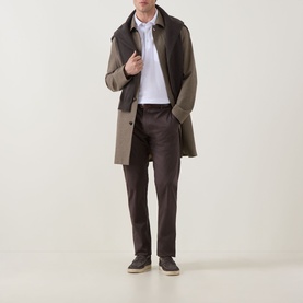 Model wearing Zegna white linen cashmere silk polo, styled with a two-tone brown overcoat and dark trousers