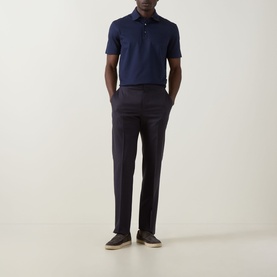 Model wearing Zegna Piquet Polo Shirt in Dark Indigo with three-button placket, styled with navy trousers and beige trainers.