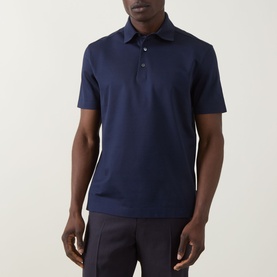 Model wearing Zegna Piquet Polo Shirt in dark indigo cotton, featuring polo collar, three-button placket and short sleeves, styled with dark trousers.