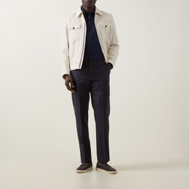 Model wearing Zegna Piquet Polo Shirt in Dark Indigo with cream overshirt jacket, navy trousers and grey suede loafers.