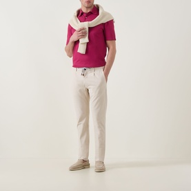 Model wearing Zegna dark pink cotton polo shirt, styled with cream trousers and a white knit scarf draped over shoulders.