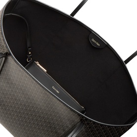 Calvin Klein Monogram Logo Tote Bag in black, open-top interior view showing inner zip pouch with gold-tone hardware and all-over monogram pattern