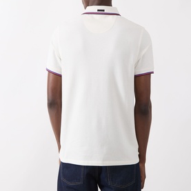 Model wearing Barbour Lure Logo Polo Shirt in Whisper White, rear view, with purple tipping detail on collar and cuffs, styled with dark jeans.