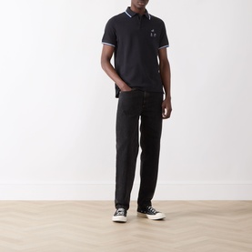 Model wearing Barbour Lure Logo Polo Shirt in Dark Navy with black jeans and black high-top trainers.