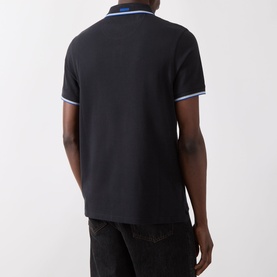 Model wearing Barbour Lure Logo Polo Shirt in Dark Navy, rear view, with light blue tipped collar and cuffs, paired with black jeans.