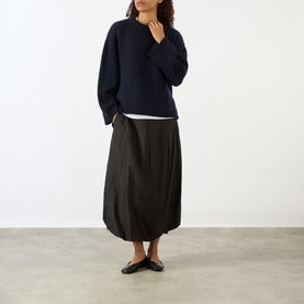 Model wearing Soft Goat navy cashmere knit sweater, styled with dark midi skirt and black flat mules.
