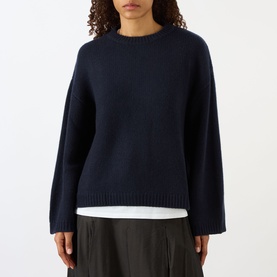 Model wearing Soft Goat navy knit jumper with crew neck and relaxed fit, styled with white top and dark trousers.