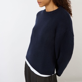 Model wearing Soft Goat navy chunky knit crew neck sweater, styled with a white layered top and black trousers