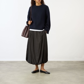 Model wearing Soft Goat navy knit jumper with dark midi skirt and black flats, carrying a burgundy shoulder bag.