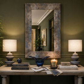 Large rectangular wall mirror with mottled bronze frame, styled on console table flanked by ceramic lamps, blue bowl and candle