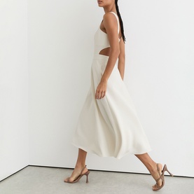 Model wearing Reiss white midi dress with cut-out waist detail and full skirt, styled with gold strappy heels