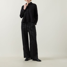 Model wearing InWear Dilana Pleated Linen Shirt in black with point collar, styled with black striped wide-leg trousers and black loafers.