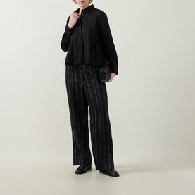 Model wearing InWear Dilana Pleated Linen Shirt in black with striped wide-leg trousers and black clutch bag.