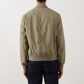Model wearing Belstaff Carrier Water-Repellent Bomber Jacket in green, rear view, with ribbed collar and cuffs, styled with dark jeans.