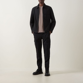 Model wearing Belstaff Compact Technical Cargo Overshirt in black with zip fastening, styled with taupe tee, black cargo trousers and boots.