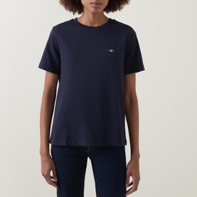Model wearing Gant Shield Logo T-Shirt in navy, featuring crew neck, short sleeves and small shield logo, styled with dark jeans