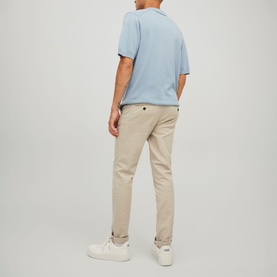 Model wearing Jack & Jones Dune chino trousers, styled with a light blue polo shirt and white trainers, rear view.