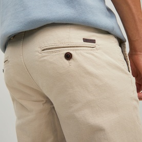 Model wearing Jack & Jones Dune chino trousers, close-up of back pocket with branded tab and brown button detail