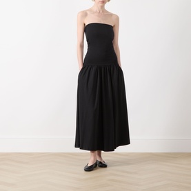 Model wearing Part Two Balina Flared Dress in black; strapless midi with fitted bodice and full skirt, styled with black flat shoes