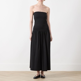 Model wearing Part Two Balina Flared Dress in black; strapless fitted bodice, gathered midi-length flared skirt, styled with black flat shoes.