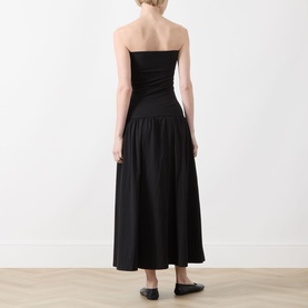 Model wearing Part Two Balina Flared Dress in black, strapless midi with fitted bodice and flared skirt, back view, styled with black flats
