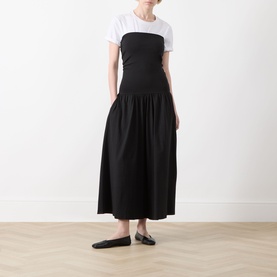 Model wearing Part Two Balina Flared Dress in black, strapless midi with fitted bodice and flared skirt, styled with white tee and black flat mules
