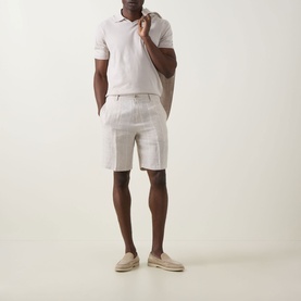 Model wearing B Cucinelli Fine Knit Polo Shirt in Juta, styled with light linen shorts and beige espadrilles.