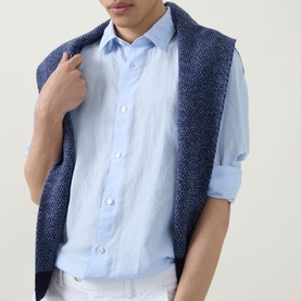 Model wearing Boggi Milano light blue linen-tencel casual shirt, paired with a navy textured knit vest, shirt sleeves rolled up.