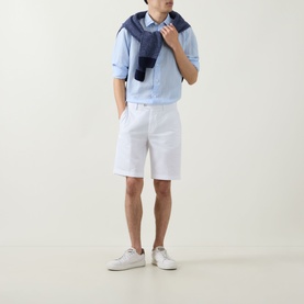 Model wearing Boggi Milano light blue tencel-linen casual shirt, styled with white shorts and white trainers, denim jacket over shoulder.
