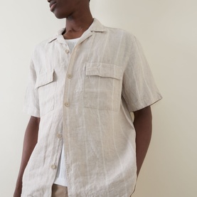 Model wearing Boggi Milano sand linen casual shirt with short sleeves, camp collar, and dual chest pockets, styled over a white top.