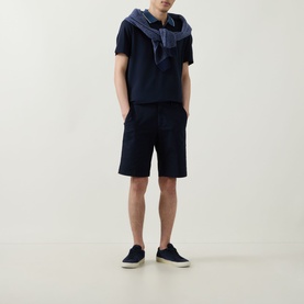 Model wearing Boggi Milano navy blue polo shirt, styled with matching shorts, a draped shirt and dark trainers.