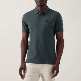 Model wearing Boggi Milano Solid Logo Piqu&eacute; Polo Shirt in green, with two-button placket, chest logo, styled with cream trousers.