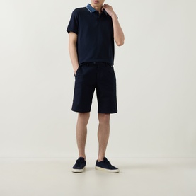 Model wearing Boggi Milano navy blue cotton shorts with a navy polo shirt and navy slip-on shoes.