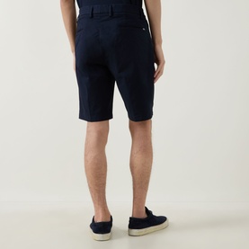 Model wearing Boggi Milano navy blue cotton shorts, shown from behind, styled with navy loafers
