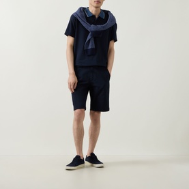 Model wearing Boggi Milano navy blue cotton shorts with navy t-shirt, scarf draped over shoulders, and navy canvas shoes.
