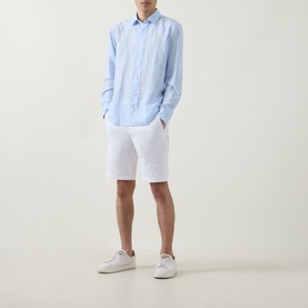 Model wearing Boggi Milano white cotton-elastane shorts with light blue linen shirt and white trainers.