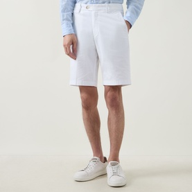Model wearing Boggi Milano white cotton shorts with hands in pockets, styled with a blue jumper and white trainers.