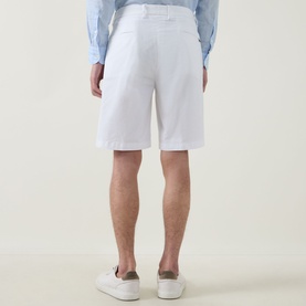 Model wearing Boggi Milano white cotton shorts, rear view, styled with a light blue shirt and white trainers.
