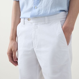 Model wearing Boggi Milano white cotton-elastane trousers, styled with a light blue linen shirt. Close-up of waistband and front pocket detail.