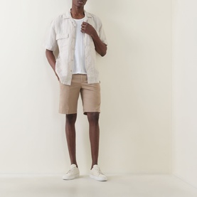 Model wearing Boggi Milano Slim-Leg Bermuda Shorts in mud, styled with a white linen shirt and white trainers.