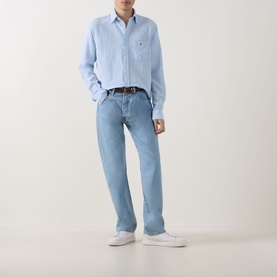 Model wearing Gant sky blue linen-cotton reg shirt with chest logo, styled with light wash jeans, dark belt and white trainers.