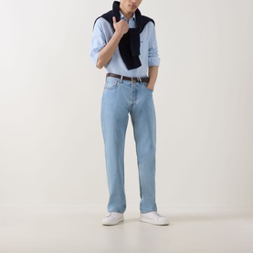 Model wearing Gant sky blue linen-cotton Reg Shirt, styled with light wash jeans, navy knitwear draped over shoulders and white trainers.