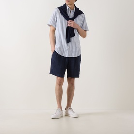 Model wearing Gant Reg Shirt in vintage blue stripe linen-cotton, styled with navy scarf, navy shorts and white trainers.