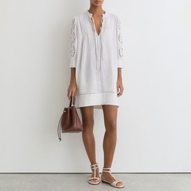 Model wearing Reiss white mini dress with broderie anglaise sleeves and pintuck detail, styled with white strappy sandals and burgundy mini bag