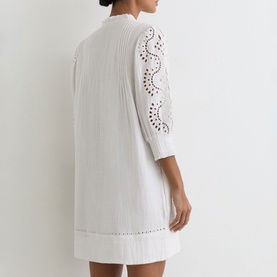 Model wearing Reiss white mini dress with broderie anglaise sleeve detail and textured cotton fabric, back view