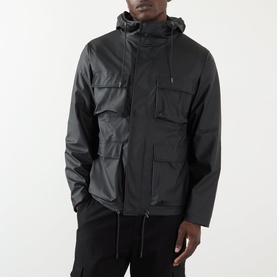 Model wearing Rains black casual jacket with hood, zip fastening, and utility chest pockets, styled with black trousers.