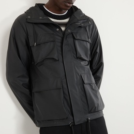 Model wearing Rains black casual jacket with hood, multiple chest pockets and zip fastening, styled with cream knit and black trousers
