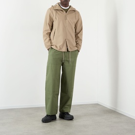 Model wearing Rains Casual Jacket in Beige with olive wide-leg trousers and black trainers