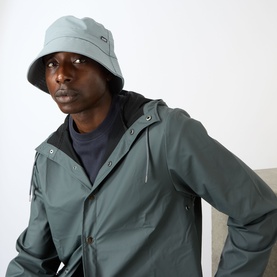 Model with Rains Water-Repellent Bucket Hat in Pool, wide brim with logo tab, styled with matching pool green jacket