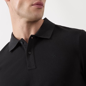 Model wearing Scotch & Soda Logo Piqu&eacute; Polo Shirt in black, showing tonal embroidered logo, two-button collar and smooth piqu&eacute; fabric